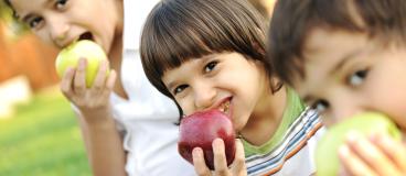 Three children eating an apple