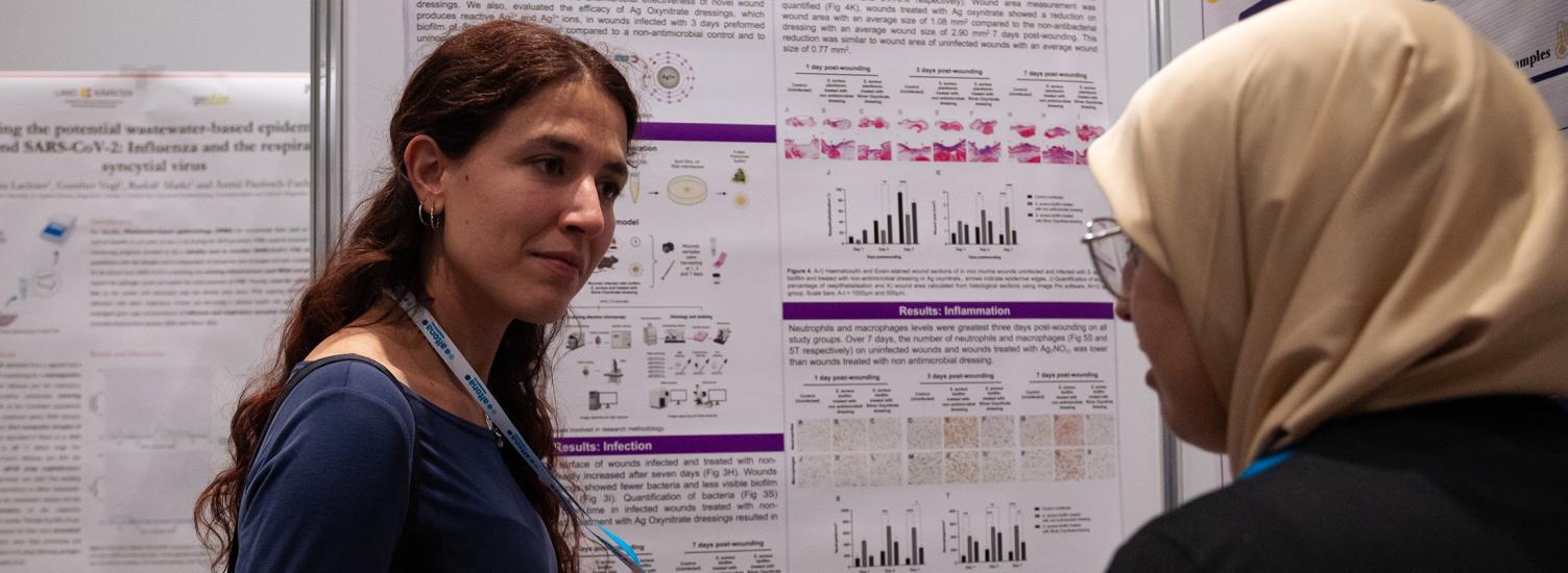 Two women in front of a scientific poster, discussing