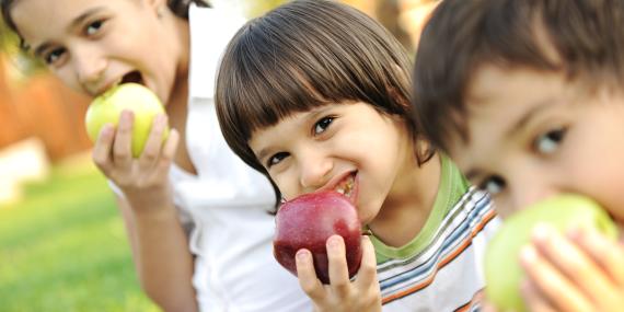 Three children eating an apple